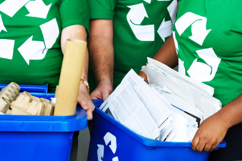 tres personas sosteniendo botes de reciclaje